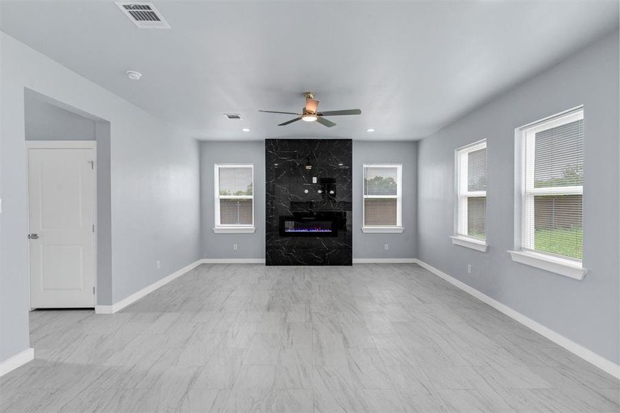 Unfurnished living room featuring a fireplace and a ceiling fan