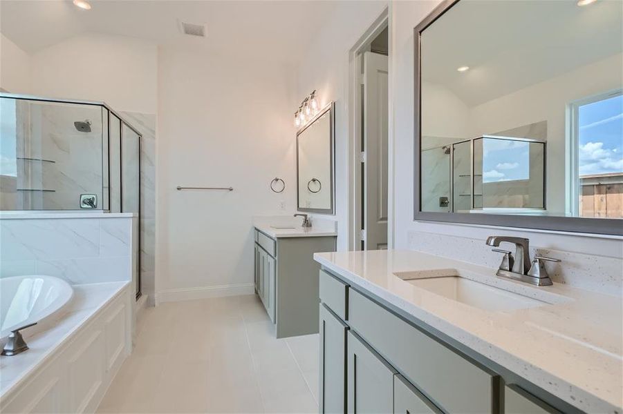 Bathroom featuring dual bowl vanity, tile flooring, lofted ceiling, and plus walk in shower