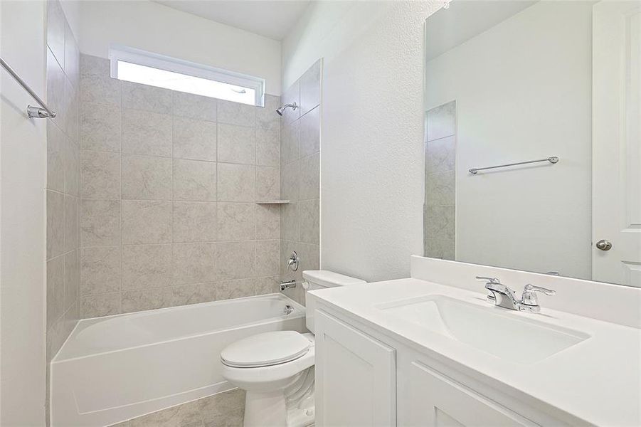 Full bathroom featuring tile patterned flooring, vanity, tiled shower / bath combo, and toilet