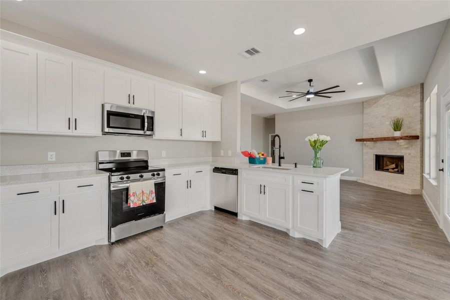 Kitchen with appliances with stainless steel finishes, light hardwood / wood-style flooring, and a tray ceiling