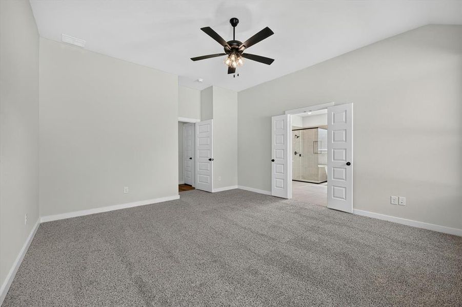 Spacious room featuring vaulted ceilings, light gray wall paint, and gray carpet flooring Spacious room featuring vaulted ceilings, light gray wall paint, and gray carpet flooring