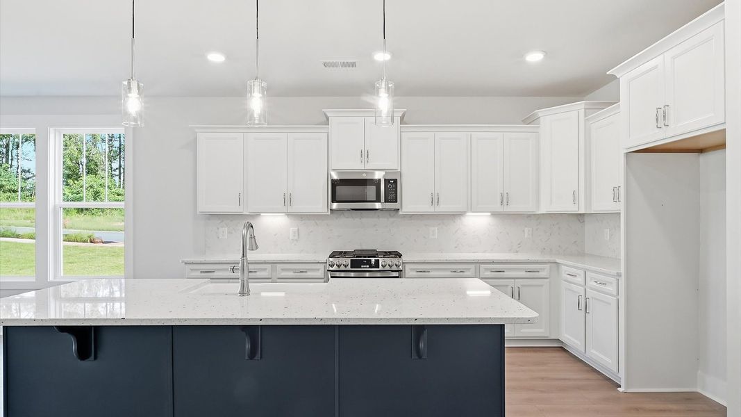 Tasteful kitchen with oversized island and stylish pendant lighting—crafted to high standards by DRB Homes