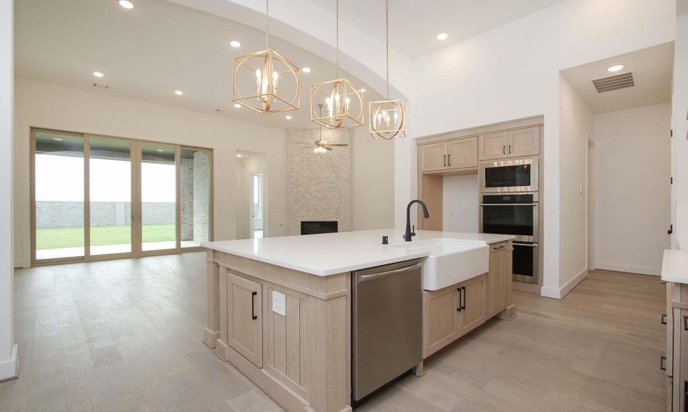 Kitchen with a chandelier, open floor plan, light wood-type flooring, stainless steel appliances, and a fireplace