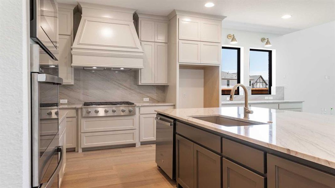 Kitchen featuring premium range hood, stainless steel appliances, decorative backsplash, light wood finished floors, and recessed lighting