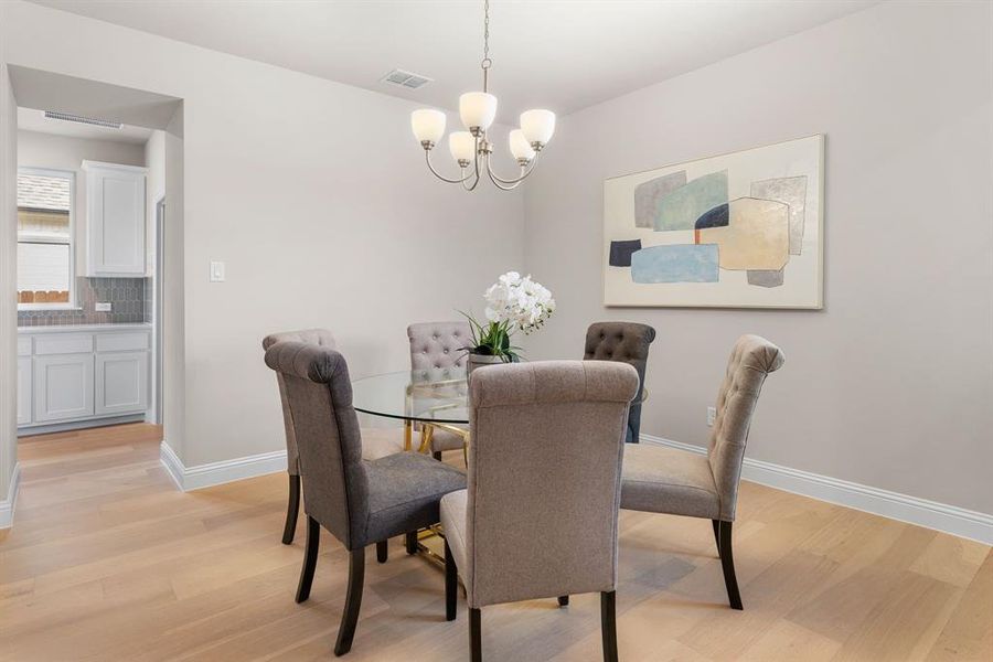 Dining space with a notable chandelier and light hardwood / wood-style floors