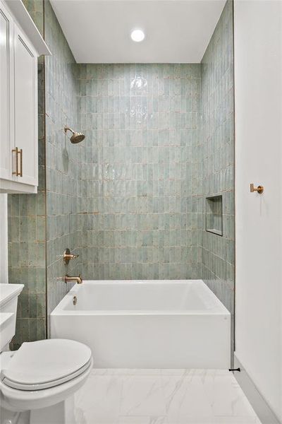 Bathroom with tile walls, bathtub / shower combination, recessed lighting, and marble finish floors Bathroom with tile walls, bathtub / shower combination, recessed lighting, and marble finish floors