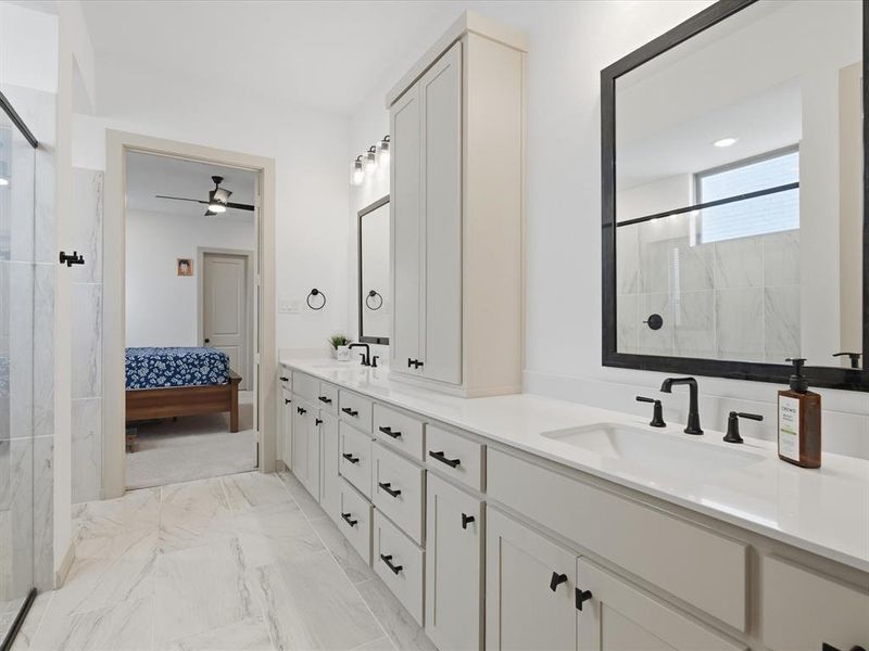 White bathroom cabinetry with matte black hardware and a built-in vertical storage cabinet