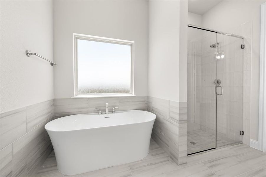 Bathroom featuring a stall shower, a freestanding bath, tile walls, and wainscoting