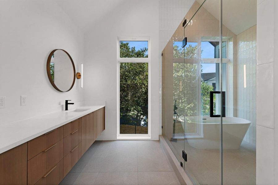 Bathroom featuring a shower stall, a soaking tub, plenty of natural light, vanity, and vaulted ceiling