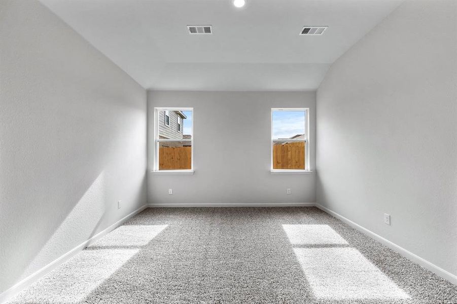 Carpeted empty room featuring vaulted ceiling