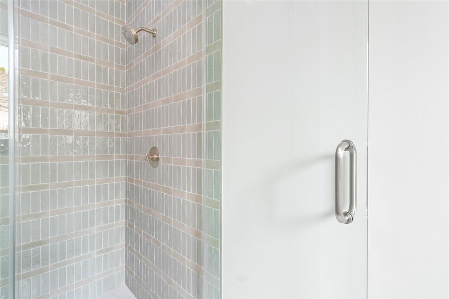 Secondary ensuite bath featuring a walk-in shower with layered tile detailing and subtle tonal variation.
