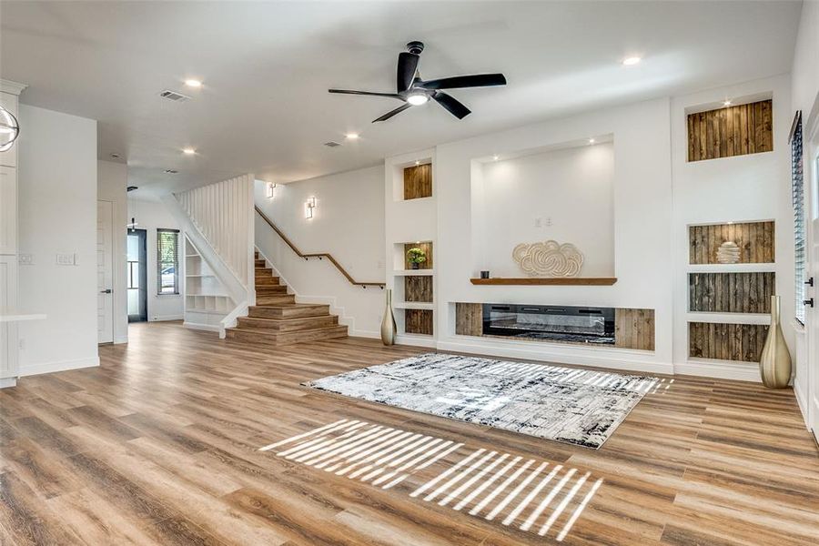 Living room with built in features, light wood-type flooring, ceiling fan, and recessed lighting