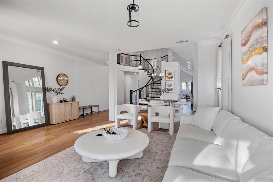 Living area with visible vents, crown molding, stairs, wood finished floors, and recessed lighting