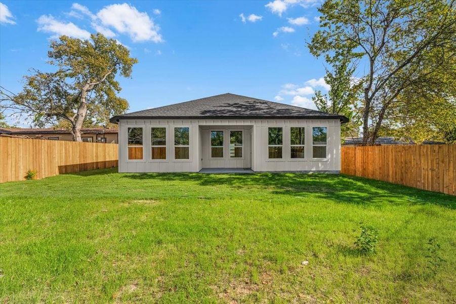 Back of house with a fenced backyard and a shingled roof