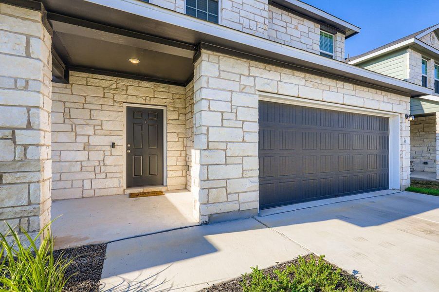 Doorway to property featuring stone siding, driveway, and an attached garage