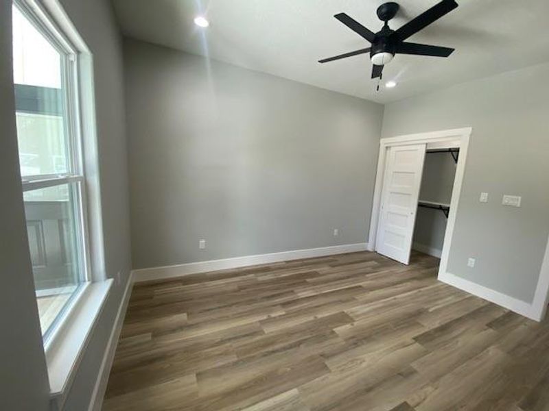 A well-lit bedroom features durable laminate flooring and a functional ceiling fan for optimal comfort. A well-lit bedroom features durable laminate flooring and a functional ceiling fan for optimal comfort.