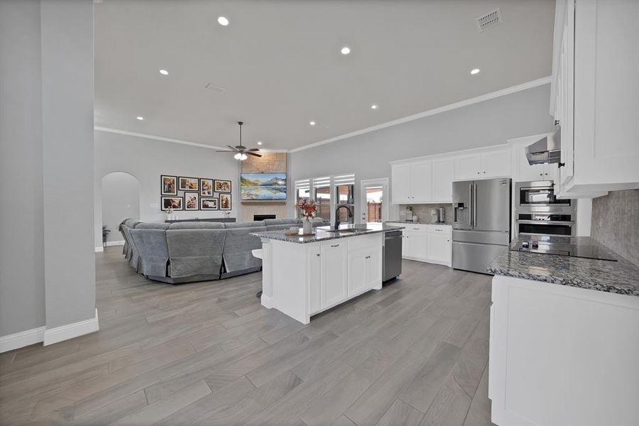Kitchen featuring appliances with stainless steel finishes, a sink, a tiled fireplace, a ceiling fan, and arched walkways Kitchen featuring appliances with stainless steel finishes, a sink, a tiled fireplace, a ceiling fan, and arched walkways