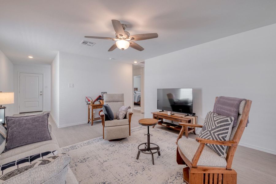 Living area with light-colored flooring, a ceiling fan, and recessed lighting