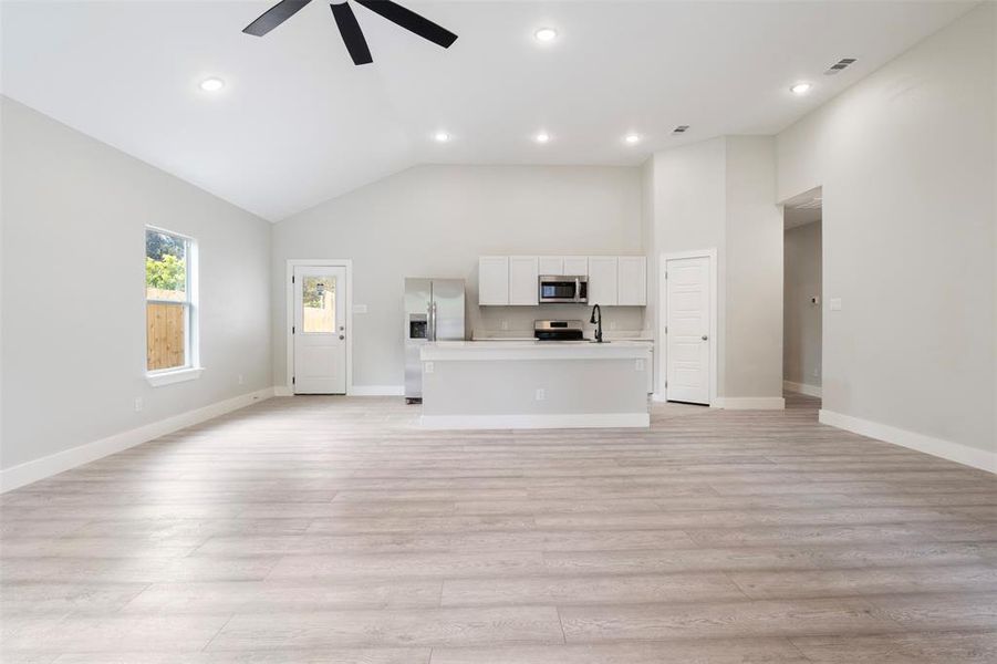 Unfurnished living room with light hardwood / wood-style floors, sink, high vaulted ceiling, and ceiling fan