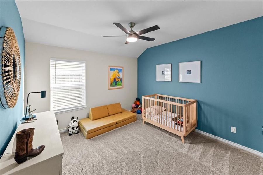 Carpeted bedroom featuring ceiling fan, vaulted ceiling