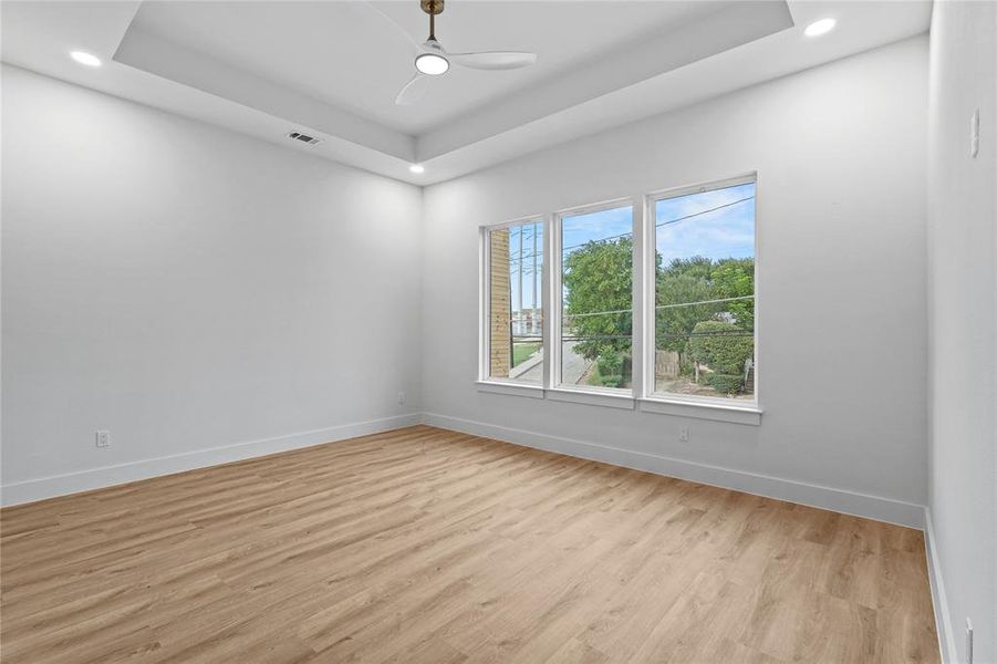 Spare room with baseboards, light wood-type flooring, a tray ceiling, recessed lighting, and a ceiling fan Spare room with baseboards, light wood-type flooring, a tray ceiling, recessed lighting, and a ceiling fan