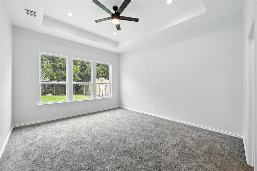 Empty room with a tray ceiling, carpet floors, a ceiling fan, and recessed lighting