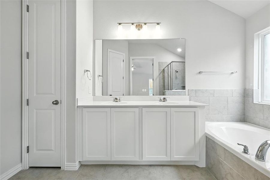 Bathroom with a stall shower, a bath, double vanity, and lofted ceiling Bathroom with a stall shower, a bath, double vanity, and lofted ceiling
