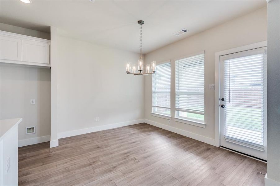Unfurnished dining area with a chandelier, light wood-style flooring, and baseboards Unfurnished dining area with a chandelier, light wood-style flooring, and baseboards