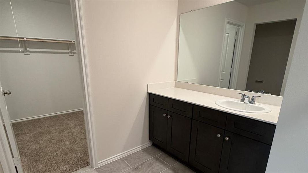 Bathroom featuring vanity, a spacious closet, light carpet, and light tile patterned floors