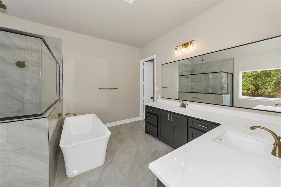 Full bathroom with a freestanding tub, a stall shower, double vanity, and light marble finish floors