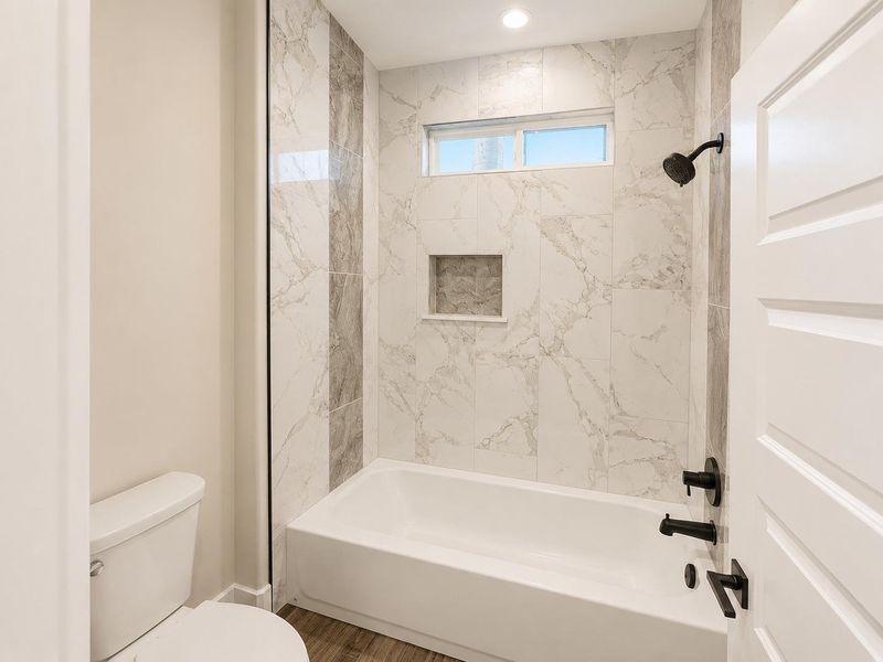 A well-appointed bathroom features a bathtub with a shower, complemented by stylish tile work.