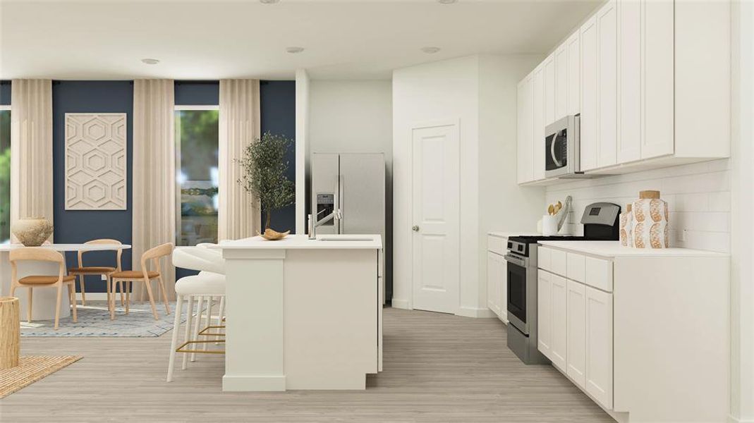 Kitchen featuring a kitchen breakfast bar, appliances with stainless steel finishes, a kitchen island with sink, white cabinets, and light wood-type flooring