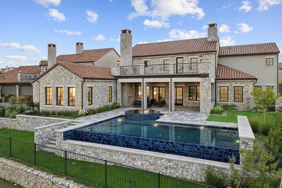 Back of house featuring a lawn, a patio area, a fenced in pool, and a balcony