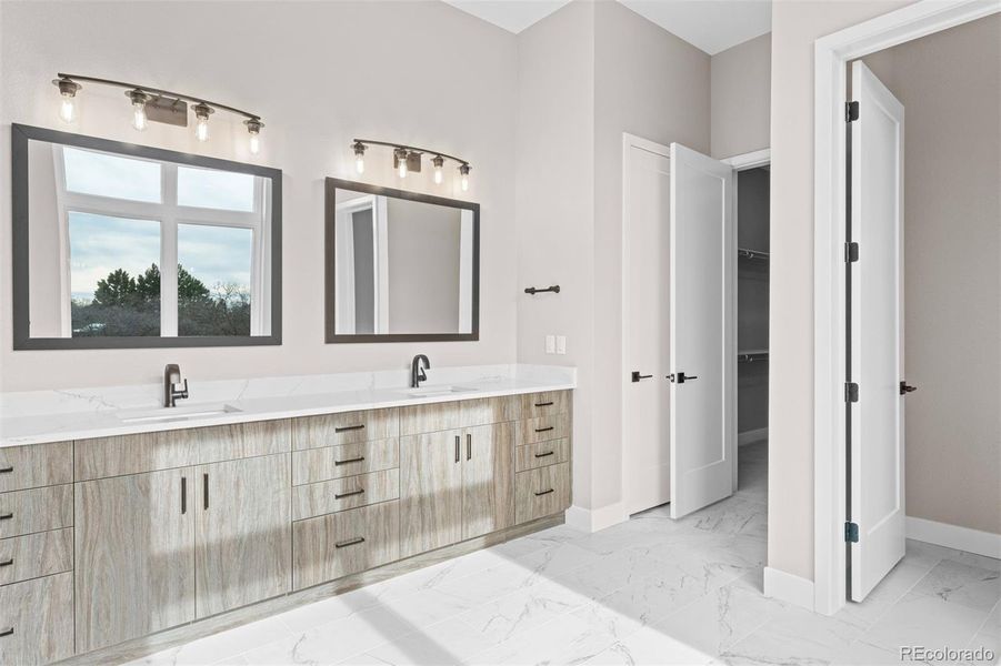 Primary bathroom with custom cabinetry, his | hers undermount sinks, and quartz countertop.