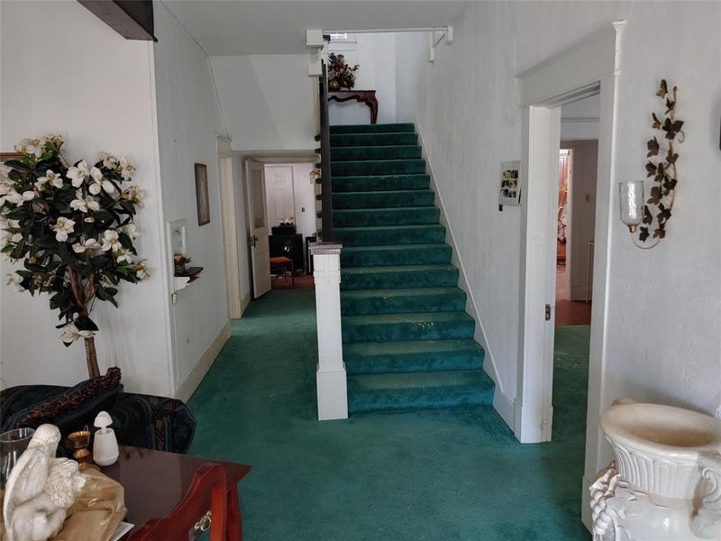 Interior entryway featuring a carpeted staircase with a white painted banister Interior entryway featuring a carpeted staircase with a white painted banister