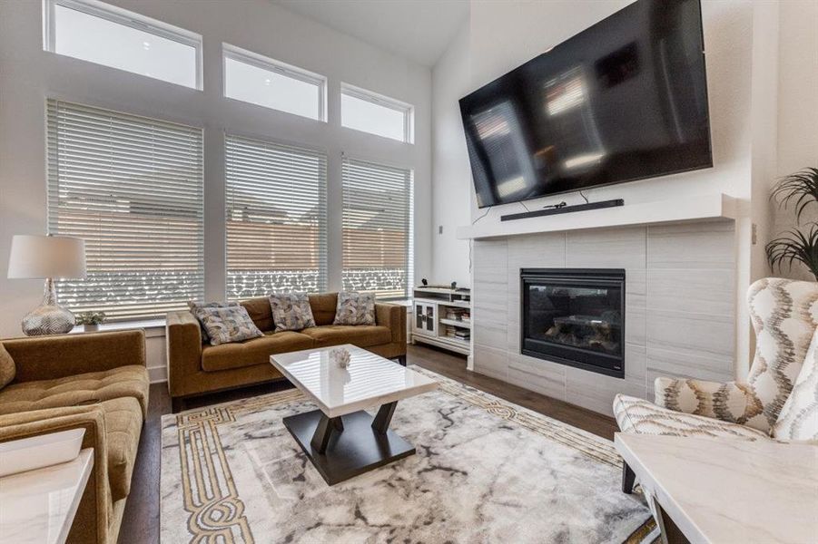 Living room featuring a high ceiling, a fireplace, and dark wood finished floors