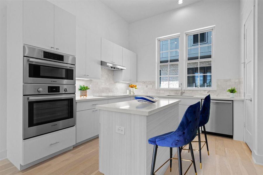 Kitchen with a breakfast bar, appliances with stainless steel finishes, white cabinets, a center island, and recessed lighting