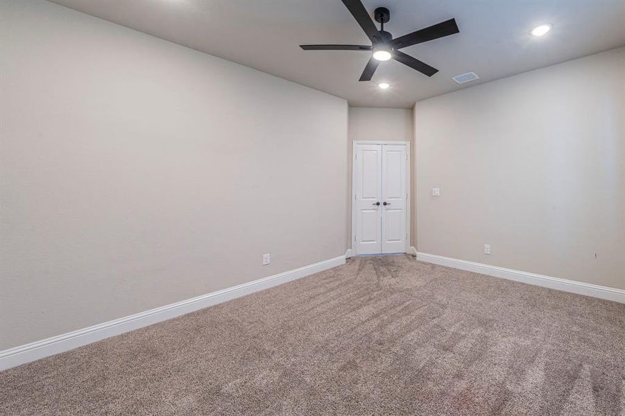 Carpeted room featuring a ceiling fan with integrated lighting, recessed lighting, double panel doors, and white baseboards