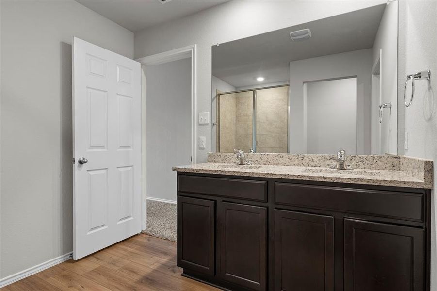 Bathroom with double vanity, a stall shower, and light wood-type flooring Bathroom with double vanity, a stall shower, and light wood-type flooring