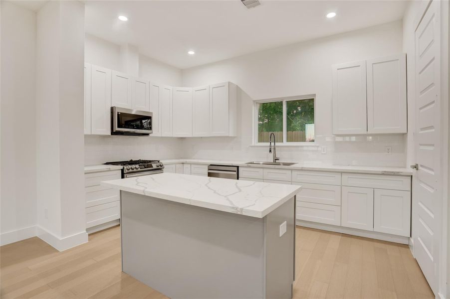 Contemporary kitchen with quartz counters, stainless Samsung appliances, and extensive cabinetry.