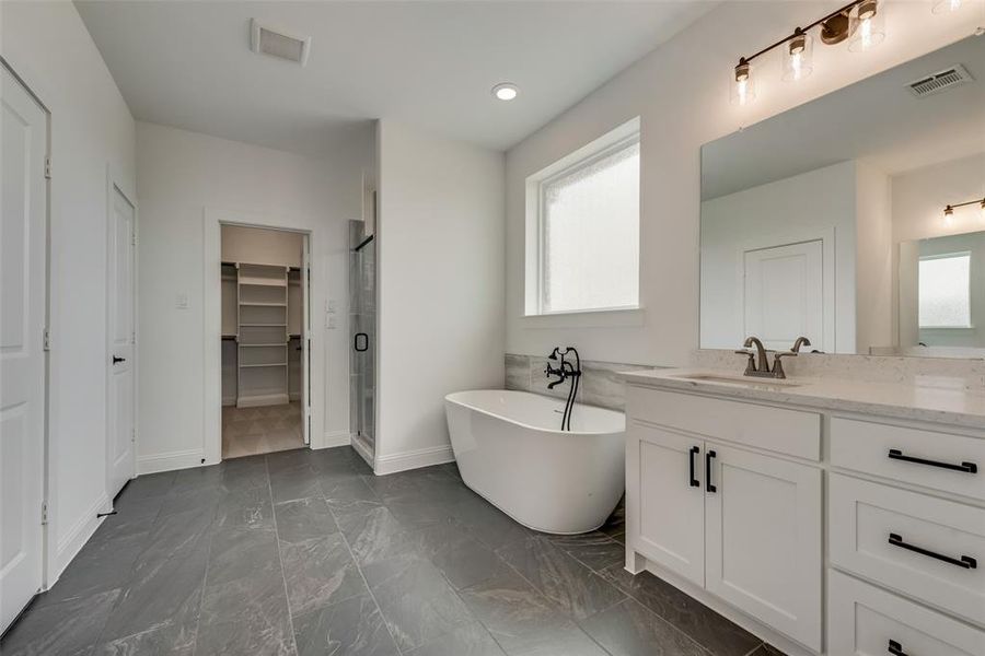 Bathroom with tile floors, plenty of natural light, vanity, and a bathtub