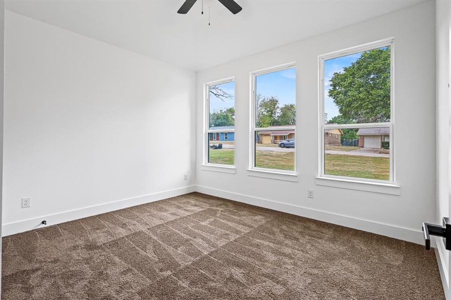 Carpeted spare room with plenty of natural light and ceiling fan