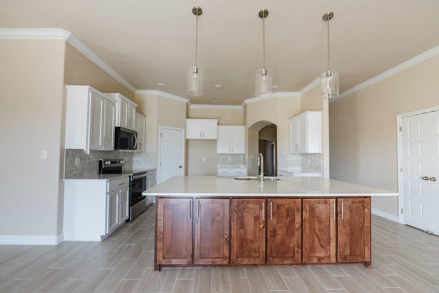 Kitchen with backsplash, appliances with stainless steel finishes, white cabinets, wood finish floors, and ornamental molding Kitchen with backsplash, appliances with stainless steel finishes, white cabinets, wood finish floors, and ornamental molding
