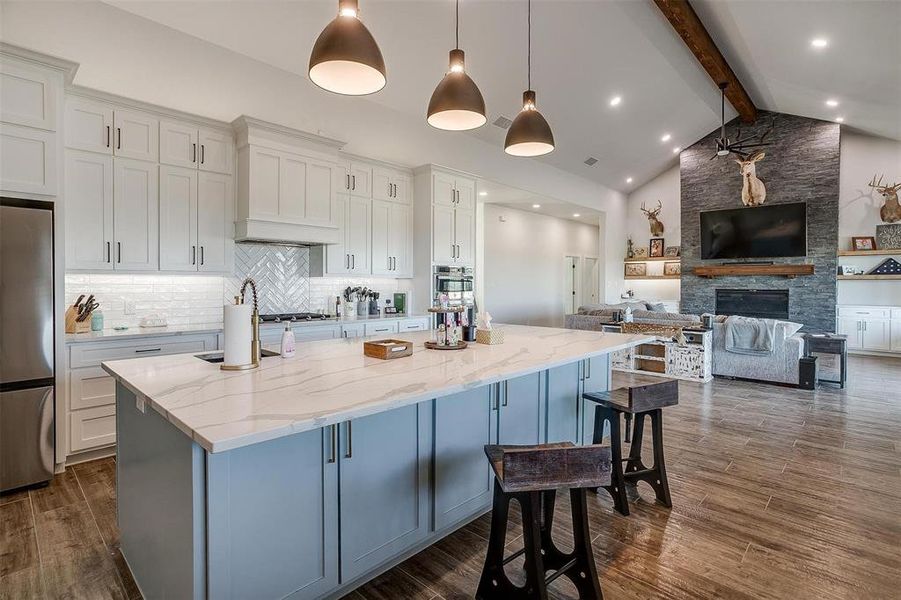 Kitchen with pendant lighting, white cabinetry, light stone countertops, and beamed ceiling