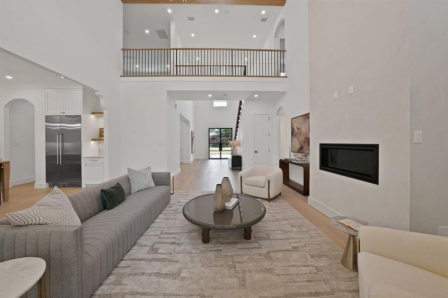 Living area featuring a two-story ceiling, recessed lighting, and wood-finish flooring