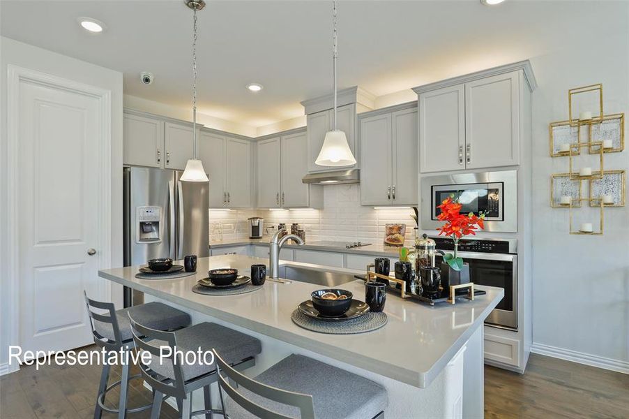 Contemporary kitchen featuring an island with seating, stainless steel appliances, pendant lighting, recessed lighting, and wood-finish flooring