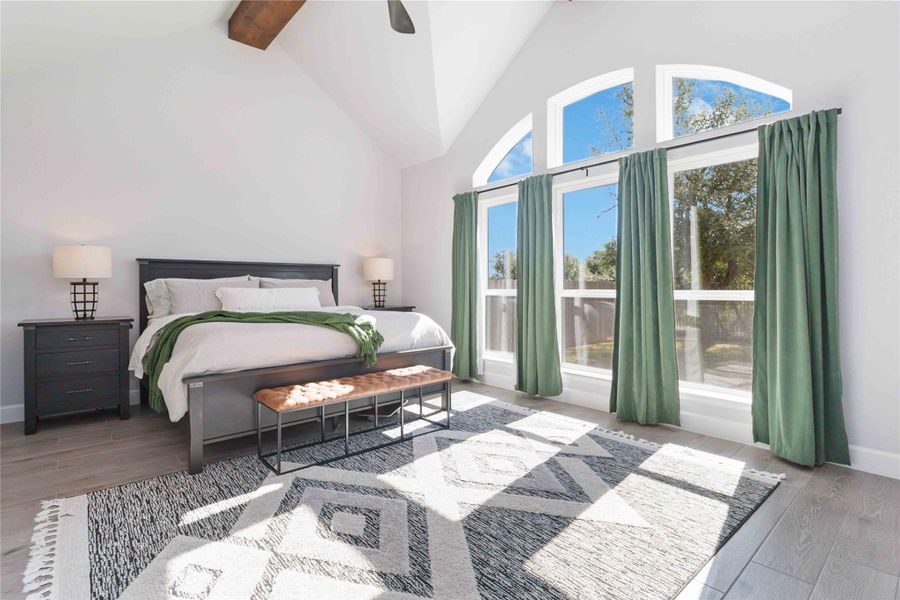 Bedroom with wood finished floors, beam ceiling, high vaulted ceiling, and ceiling fan Bedroom with wood finished floors, beam ceiling, high vaulted ceiling, and ceiling fan