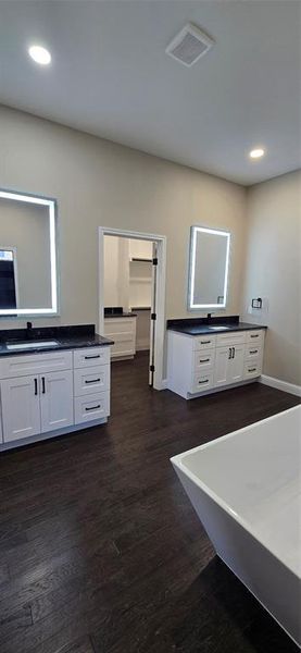 Full bathroom featuring two vanities, anti fog smart touch mirrors, dark wood-type flooring, a freestanding bath, and recessed lighting Full bathroom featuring two vanities, anti fog smart touch mirrors, dark wood-type flooring, a freestanding bath, and recessed lighting