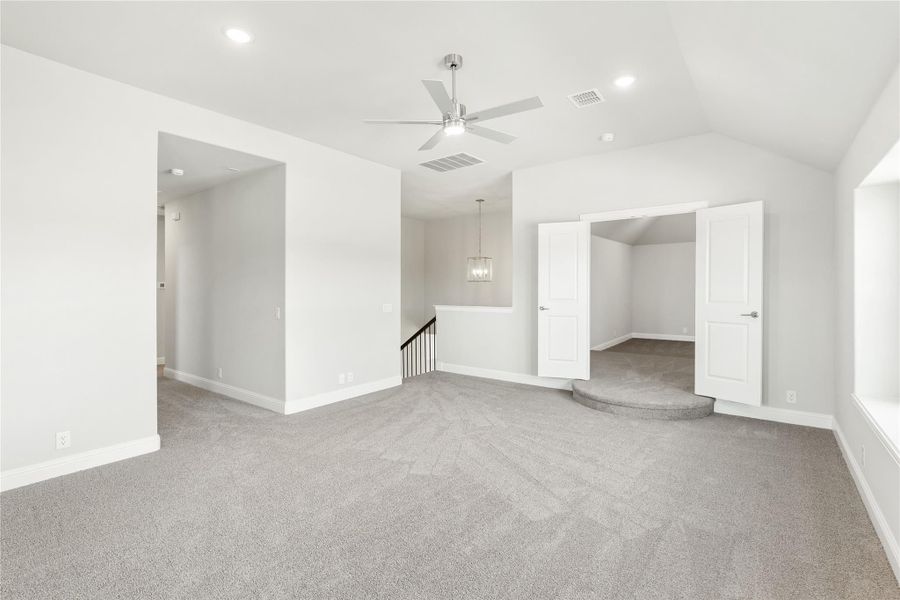 Large open upstairs loft with gray carpet, ceiling fan, staircase landing, and double doors leading to a bonus room. Large open upstairs loft with gray carpet, ceiling fan, staircase landing, and double doors leading to a bonus room.