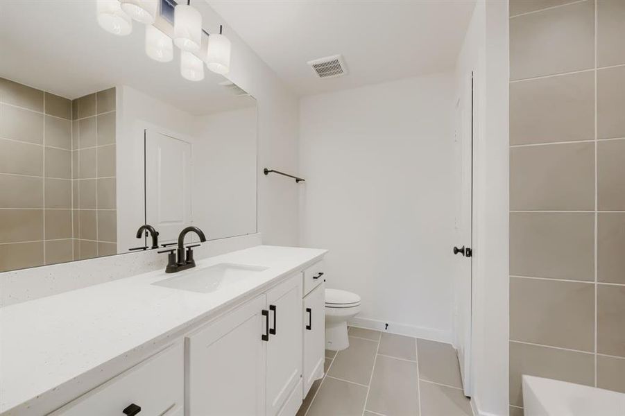 Bathroom vanity featuring white cabinetry with dark hardware, a white countertop, and an integrated sink with a dark faucet